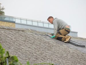 man putting tiles on Exeter house's roof