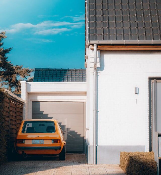 side of a house garage and orange car parked outside