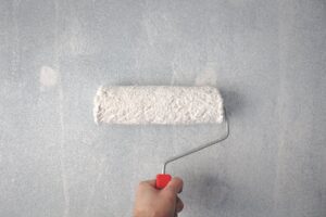 person using a paint roller on wall